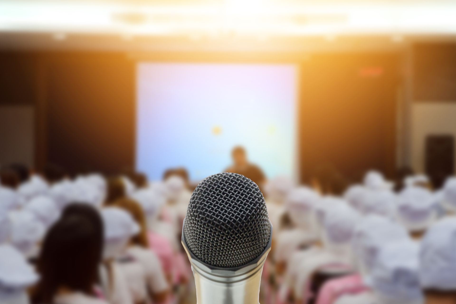 Microphone over the Abstract blurred photo of conference hall or seminar room with attendee background,Small Business training concept,Public speaking using as background and wallpaper.
