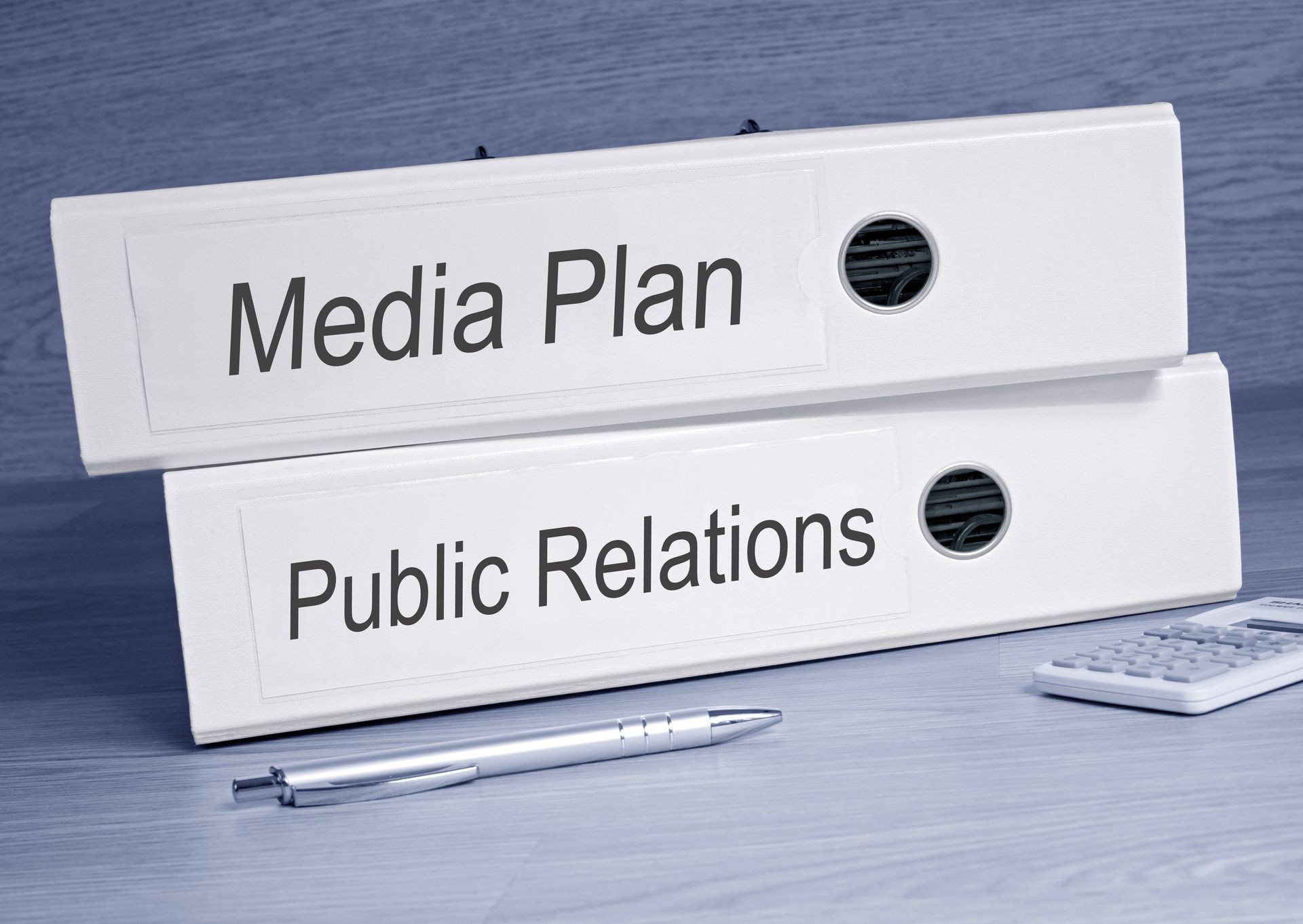 Media Plan and Public Relations - two white binders with text on desk in the office